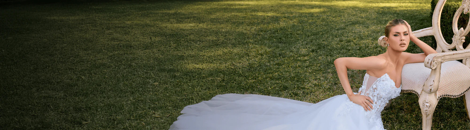 Woman in a white wedding dress sitting on a bench in a park